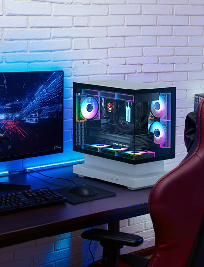 Gaming setup with a computer monitor, keyboard, mouse, and RGB-lit PC case against a white brick wall.