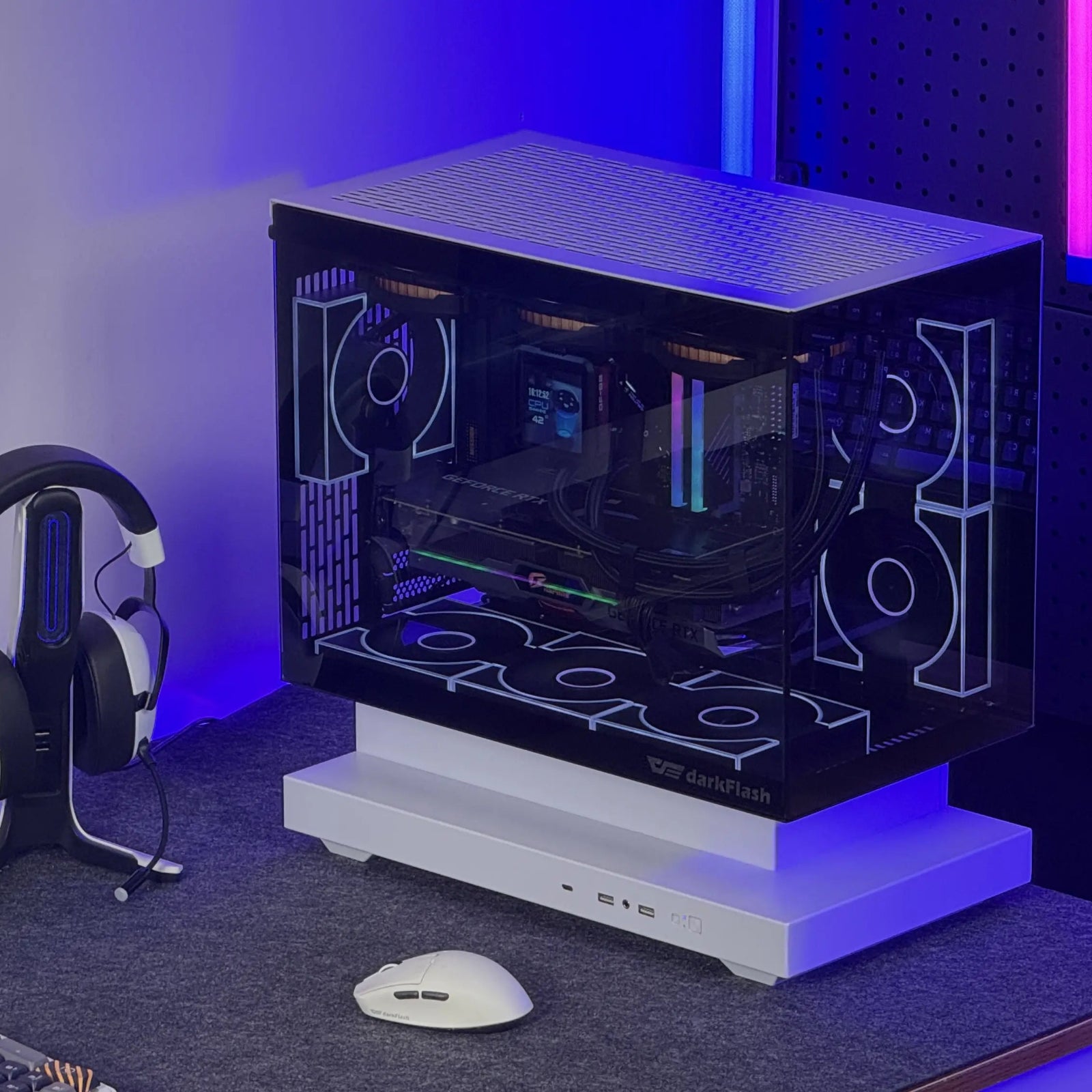 Gaming setup with computer monitor, headset, and open computer case on a desk.